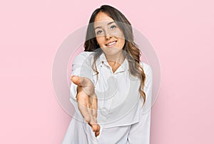 Young brunette woman wearing casual clothes smiling friendly offering handshake as greeting and welcoming