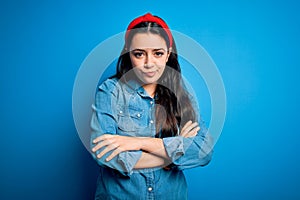 Young brunette woman wearing casual denim shirt over blue isolated background skeptic and nervous, disapproving expression on face
