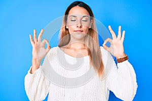 Young brunette woman wearing casual sweater relax and smiling with eyes closed doing meditation gesture with fingers