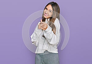 Young brunette woman wearing casual turtleneck sweater pointing fingers to camera with happy and funny face