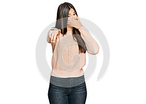 Young brunette woman wearing casual winter sweater laughing at you, pointing finger to the camera with hand over mouth, shame