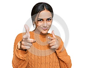 Young brunette woman wearing casual winter sweater pointing fingers to camera with happy and funny face
