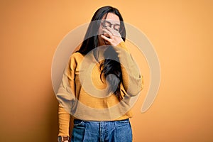 Young brunette woman wearing glasses and casual sweater over yellow isolated background tired rubbing nose and eyes feeling