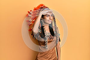 Young brunette woman wearing indian costume very happy and smiling looking far away with hand over head