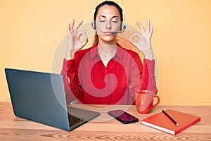 Young brunette woman wearing operator headset at the call center office relax and smiling with eyes closed doing meditation