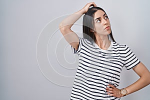 Young brunette woman wearing striped t shirt confuse and wondering about question
