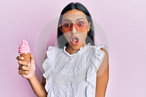 Young brunette woman wearing summer style holding ice cream scared and amazed with open mouth for surprise, disbelief face