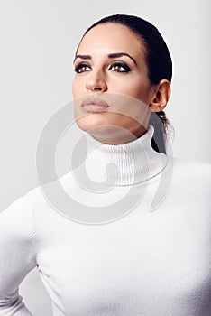 Young brunette woman wearing white poloneck in studio shot