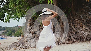 Young brunette woman in white drees and hat running on tropical beach. slow motion. 3840x2160