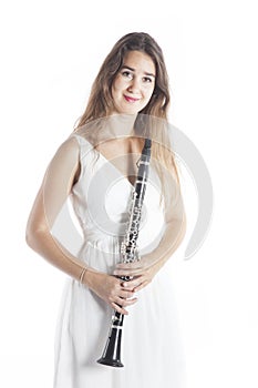 Young brunette woman in white dress holds clarinet in studio and