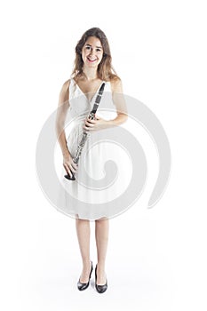 Young brunette woman in white dress holds clarinet in studio and