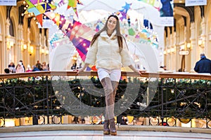 Young brunette woman in white fur coat and high suede boots