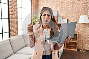 Young brunette woman working as real state agent holding keys of new home depressed and worry for distress, crying angry and