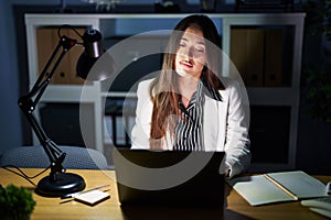 Young brunette woman working at the office at night with laptop looking sleepy and tired, exhausted for fatigue and hangover, lazy