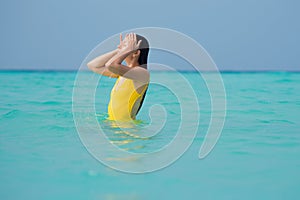 Young brunette woman in yellow one piece swimsuit.