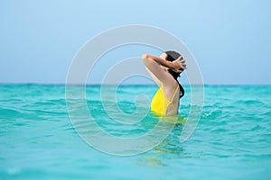 Young brunette woman in yellow one piece swimsuit.