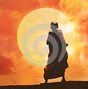 Young Buddhist monk on orange sunset