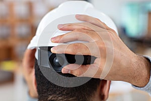 Young builder adjusting helmet by hands