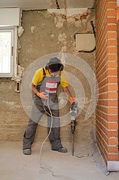 Young builder checking the jackhammer wire because it is not working.