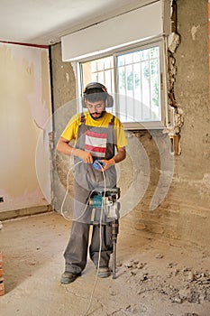 Young builder checking the jackhammer wire because it is not working.