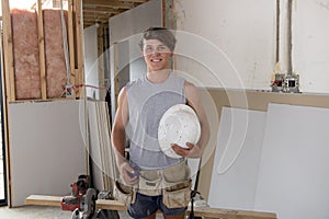 Young builder industry trainee man on his 20s wearing protective helmet learning working at industrial workshop site