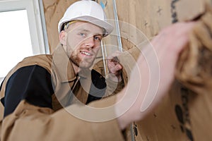 Young builder insulating walls in room
