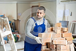 Young builder is laying bricks on top of each other