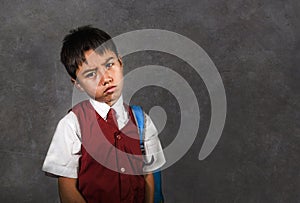 Young bullied abused schoolboy in uniform carrying school bag sad depressed on blackboard feeling a lonely and stressed kid victim