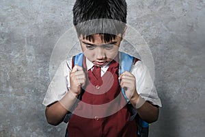 Young bullied abused schoolboy in uniform carrying school bag sad depressed on blackboard feeling a lonely and stressed kid victim