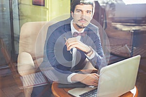 Young businesman working at cafe, using laptop