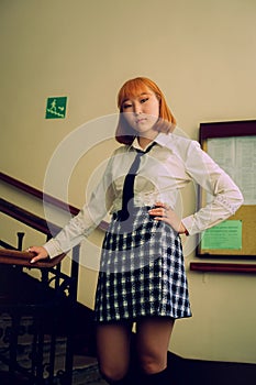 A young business Asian student in uniform stands on the stairs of the institute where she is studying for an exchange.Education in