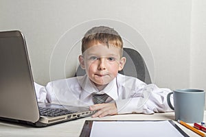 Young business boy is working in the office. A child disguised as a businessman. Funny kids