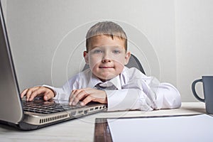 Young business boy is working in the office. A child disguised as a businessman. Funny kids