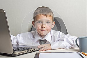 Young business boy is working in the office. A child disguised as a businessman. Funny kids