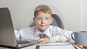 Young business boy is working in the office. A child disguised as a businessman. Funny kids