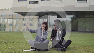 Young business colleagues having fun outdoors, sitting outside office and taking a selfie