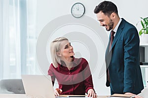 young business colleagues smiling each other while working together