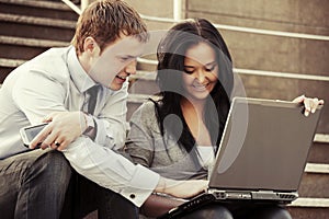 Young business couple with laptop on the steps