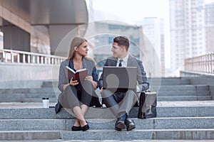 Young business couple sitting on stairs near office building.