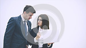 Young business couple standing, looking at something in the laptop, discussing important questions, thinking.