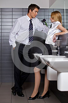 Young business couple talking intimately in office washroom