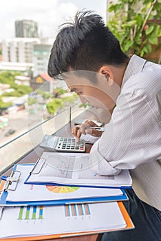 Young business employee using calculator to check the reports