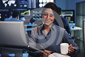 Young business female or broker working on finance trading with laptop computer. Investiment woman looking at camera at photo