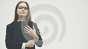 Young business girl stands on a white background and reads a document carefully.
