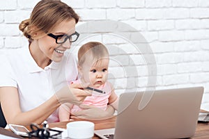 Young business lady entertains cute baby.