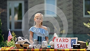 Young business lady selling old toys on yard sale, earning extra pocket money