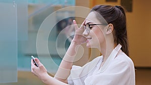 Young business lady uses a smartphone. surprised girl in white shirt and glasses makes a phone call.