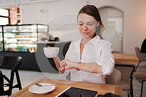 Young business lady working in cafe. Attractive woman in white shirt. Formal portrait