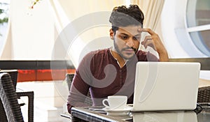 Young business man Blogger sitting at laptop, smartphone and cup of coffee. Student learning online