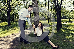 Young business man and business woman working and drinking coffee in a public park